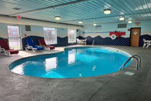 a large swimming pool in a room with chairs and tables at Baymont by Wyndham Indianapolis Northeast in Indianapolis
