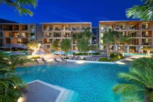 a swimming pool in front of a hotel at night at Wyndham Grand Nai Harn Beach Phuket in Nai Harn Beach
