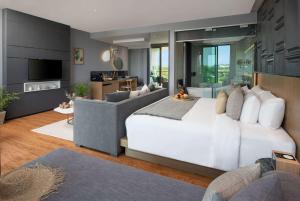 a bedroom with a white bed and a living room at Wyndham Grand Nai Harn Beach Phuket in Nai Harn Beach