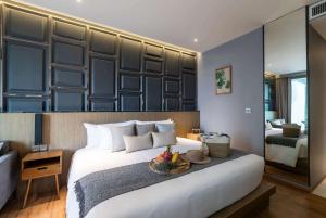 a bedroom with a large bed with a bowl of fruit on it at Wyndham Grand Nai Harn Beach Phuket in Nai Harn Beach