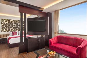 ガントクにあるRamada by Wyndham Gangtok Hotel & Casino Goldenのベッドと赤いソファのあるホテルの部屋