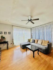 a living room with a couch and a ceiling fan at Feel at Home Polomolok WiFi 300mbps Netflix 75in TV in Polomolok