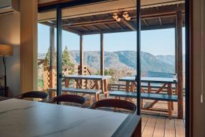 a room with tables and chairs and a balcony with mountains at Villa Noël Hakone Skylight Sauna & Open Air Bath in Hakone