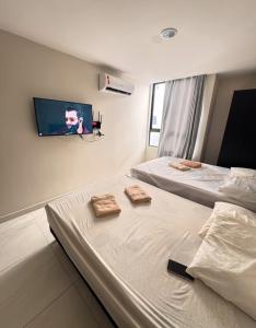 two beds in a hotel room with two towels at Flat alto padrão Intermares in Cabedelo