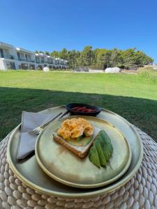 a plate of food on a table with a sandwich at Oikos Sani Suites in Sani Beach