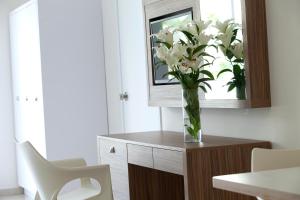 a vase of white flowers on a wooden cabinet at Princessa Vera Hotel Apartments in Paphos