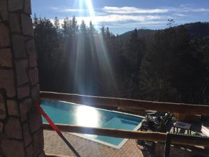 a swimming pool on a deck with the sun shining through the trees at Villa Lake Palace in Berovo