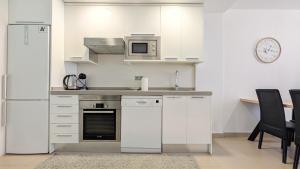 eine weiße Küche mit einem Kühlschrank und einer Mikrowelle in der Unterkunft MIRADOR lovely apartment in Benidorm