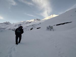 a man walking through the snow on a snow covered mountain at Gangzing Homestay in Tāndi