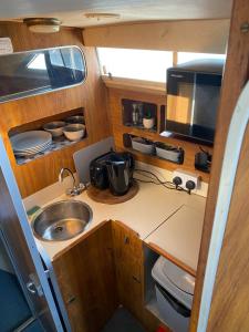 a small kitchen with a sink and a microwave at The River Thames - Surrey Boat in Thorpe +18 photos