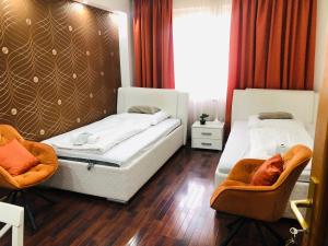 a bedroom with two beds and two chairs at Éjjelibagoly Vendégház in Szentes