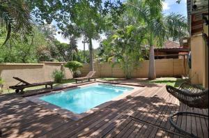 a swimming pool with two benches on a wooden deck at Gecko Cottages in Hectorspruit