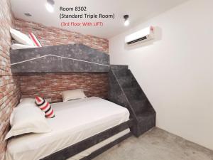 a bed in a room with a brick wall at Mwv Family Suite Room in Muar