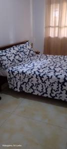 a bed with a black and white comforter on it at White home in Dodangoda