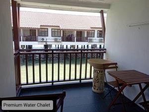 a room with a balcony with a table and a bench at Alpine Premium Water Chalet 2 in Port Dickson