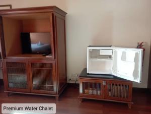 a entertainment center with a tv and a wooden cabinet at Alpine Premium Water Chalet 2 in Port Dickson +4 photos