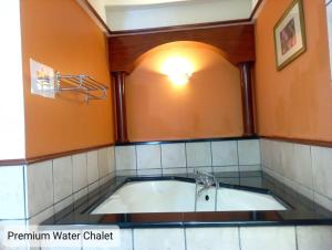 a bath tub in a bathroom with an orange wall at Alpine Premium Water Chalet 2 in Port Dickson