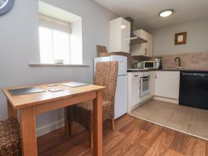 Il comprend une cuisine avec une table et des chaises en bois ainsi qu'une cuisine équipée d'un réfrigérateur. dans l'établissement The Cottage, à Thirsk