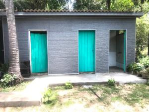 due porte verdi su un edificio grigio con una palma di Salt Bay Kite and Dive Resort a Kalpitiya Altre 74 foto