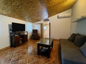 a living room with a couch and a flat screen tv at Alojamiento Rural Casa Águila con piscina privada para 6 personas in Los Valverde