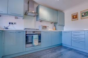 una cocina azul con armarios y electrodomésticos blancos en Hot Tub, Private Parking, King Bed, Beach luxury, en Cleethorpes