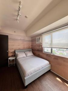 a bedroom with a large bed with a window at Cozy Cove - Avida Aspira Tower 1 in Cagayan de Oro