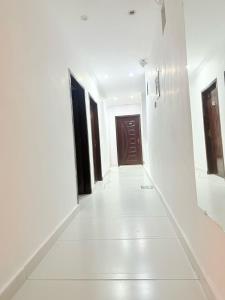 a corridor with white walls and a brown door at Hotel Tulip Inn, Gulberg in Lahore