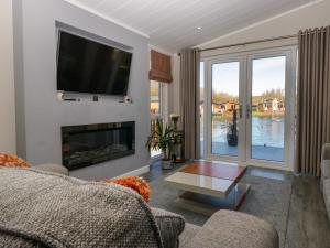 un salon avec une cheminée et une télévision dans l'établissement Coniston View Lodge, à Carnforth
