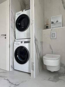 una lavatrice e un'asciugatrice in un bagno con servizi igienici di Villa neuve avec piscine 3 chambres 140 m2 a Calvi