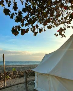 a white tent on a beach with the ocean at KAWAI Beach Camp in Lobo +15 photos