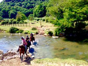 a group of people riding horses crossing a river at OAK Glamping Relax in Manziana