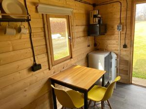 un tavolo e sedie in legno in una casetta minuscola di Woodland Cabin Camping de Regenboog a Šluknov