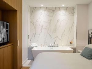 a bedroom with a tub and a white marble wall at Sofitel Roma Villa Borghese in Rome