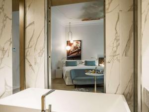 a bathroom with a tub and a bedroom with a bed at Sofitel Roma Villa Borghese in Rome