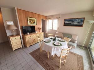 a living room with a table and chairs and a television at Echappée Marine - Plage du Grau-du-Roi in Le Grau-du-Roi