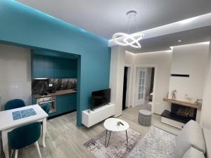 a living room with a blue wall and a kitchen at RentRoom Ajan Apartment in Pogradec