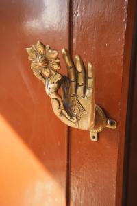 a bronze hand holding a flower on a door at Gyanman Homes in Kathmandu