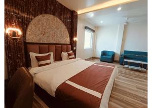 a bedroom with a large bed and a blue couch at Celestial Inn in Prayagraj +22 photos