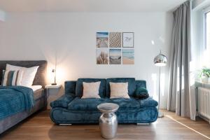 un soggiorno con divano blu e sedia di Ankerherz Appartements bei Blankenese ad Amburgo