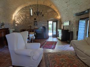 a living room with white chairs and a stone wall at Le Due Querce in Vicolo Rancolfo +48 photos