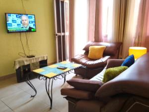 a living room with a couch and a table and a tv at Appart Meublé Yaoundé Odza in Odza I