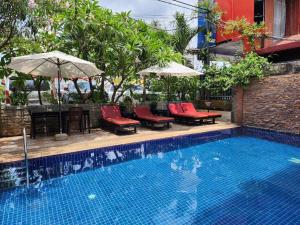 a swimming pool with chairs and umbrellas next to a building at Jasmine Lodge Siem Reap in Siem Reap