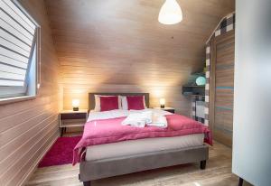 una camera da letto con un letto grande in una parete di legno di FLAUTA Całoroczne domki z prywatną balią, sauną i jacuzzi a Sianozety