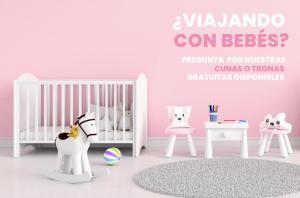 a pink room with a crib and two tables at Cabaña junto al Río y Montañas I AndBnB in Canillo