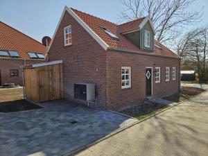 a brick house with a gate and a garage at Ferienhaus Mühle 7 in Krummhörn