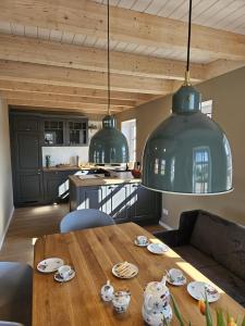 a kitchen with a wooden table and two green pendant lights at Ferienhaus Mühle 7 in Krummhörn