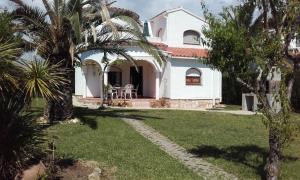 a white house with palm trees in front of it at Villa ANATMA in Les tres Cales