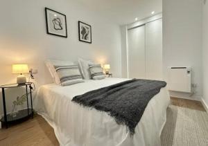 a bedroom with a white bed with a black blanket at Apartamento temporal cómodo y moderno para estancias personales o profesionales in Coslada