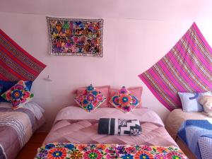 a room with two beds with colorful pillows on them at Wiñay UTA lodge in Puno