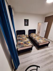 two beds in a room with blue curtains at Apartmani Terra in Vukovar